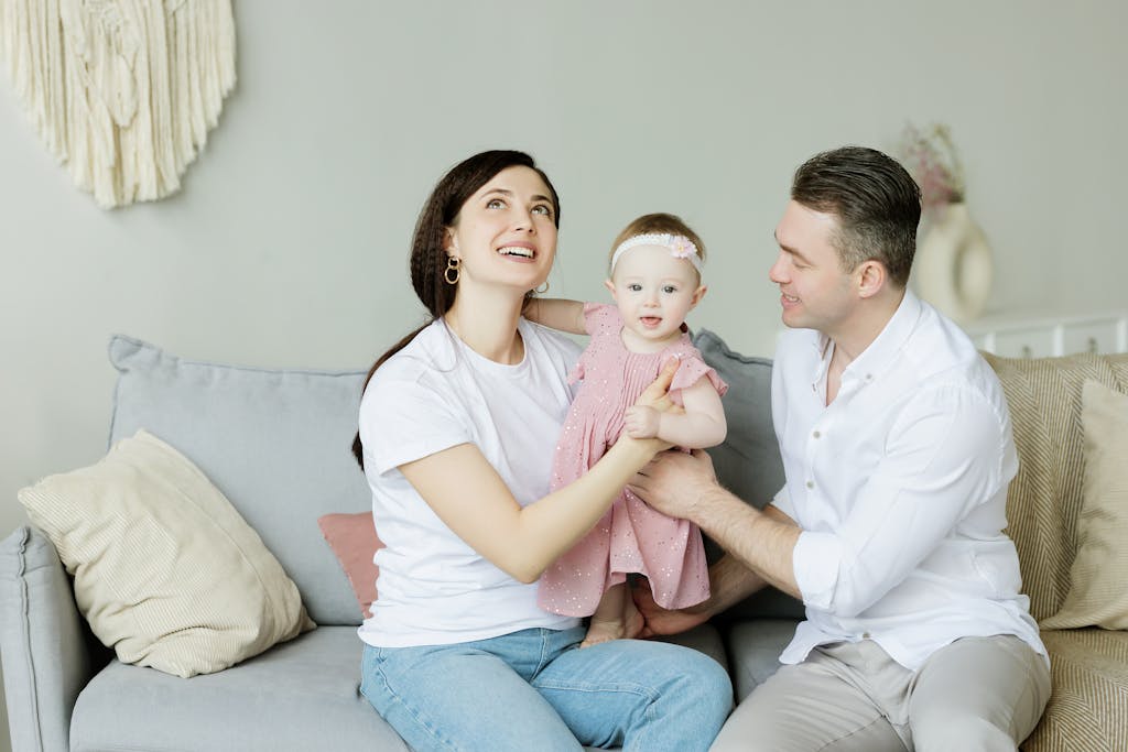 Smiling family with a toddler enjoying quality time on the couch at home.